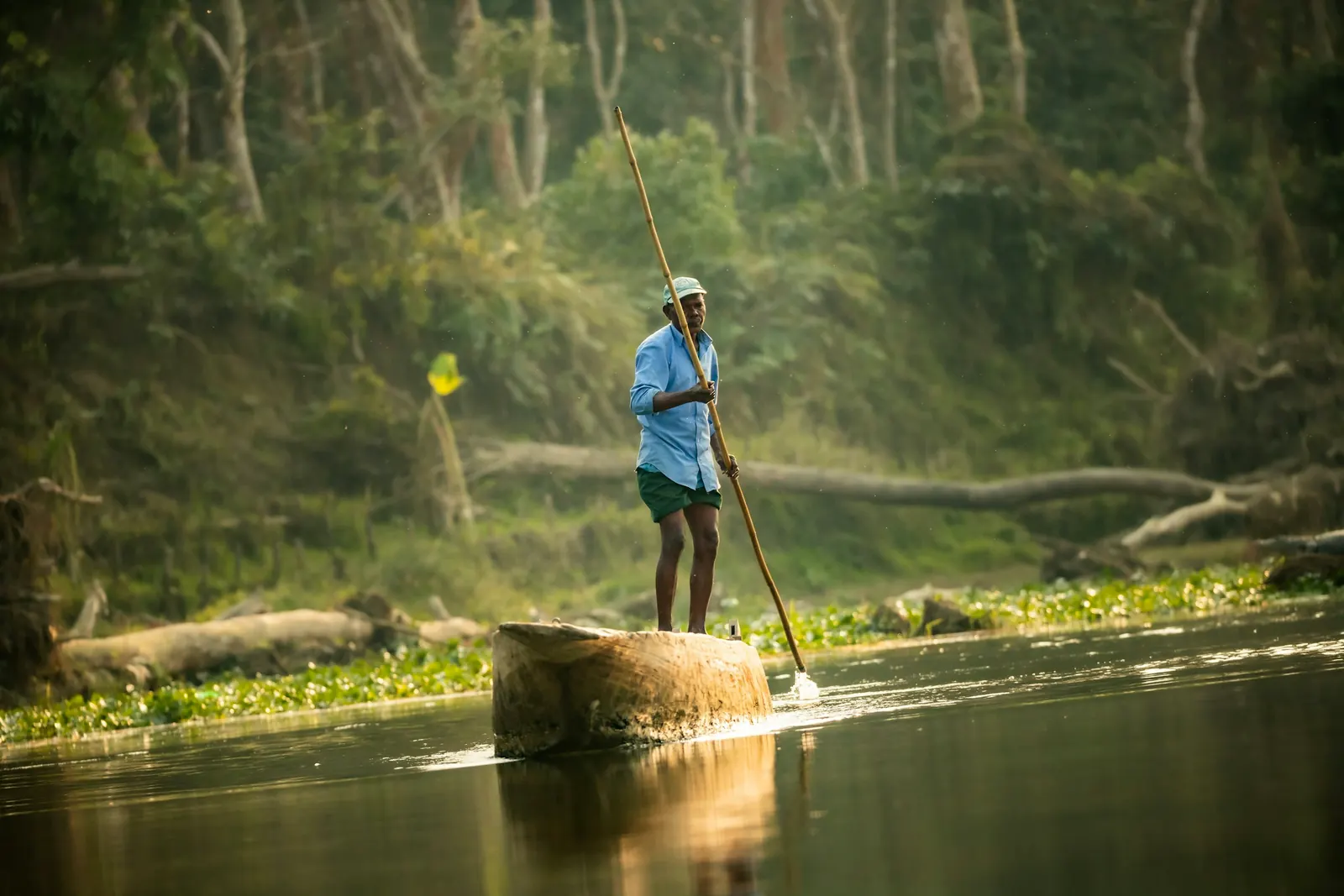 Hombre navegando un río de la selva con una vara, entre la bruma