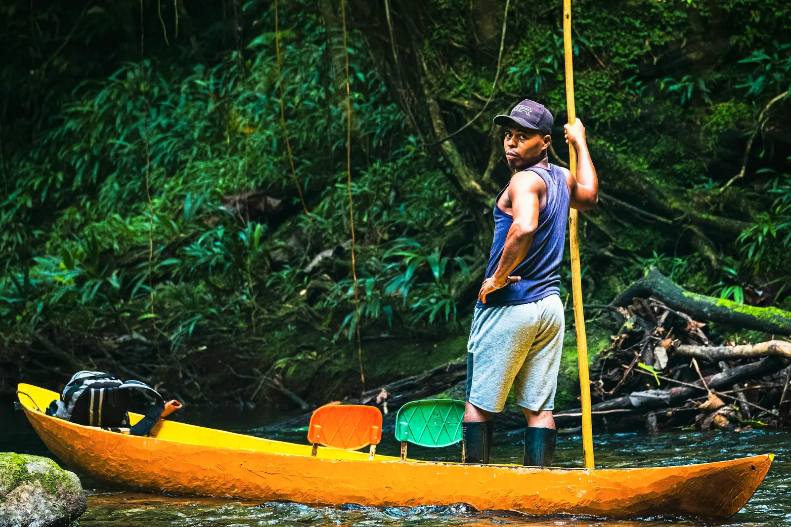 Pescador de pie en una canoa amarilla en un río de la selva